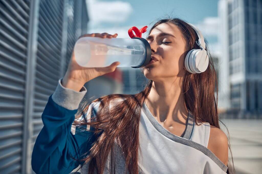 Elektrolyty: Co to je a jak vybrat ty nejlepší pro vaše potřeby? žena pije elektrolyty
